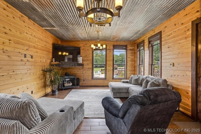 3892 Folsom Rd, Durant, OK 74701 - living room with a chandelier, wooden walls, a wood stove, and hardwood / wood-style flooring