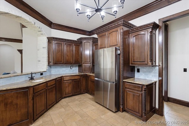 3892 Folsom Rd, Durant, OK 74701 - kitchen with freestanding refrigerator, arched walkways, light stone countertops, crown molding, and decorative backsplash