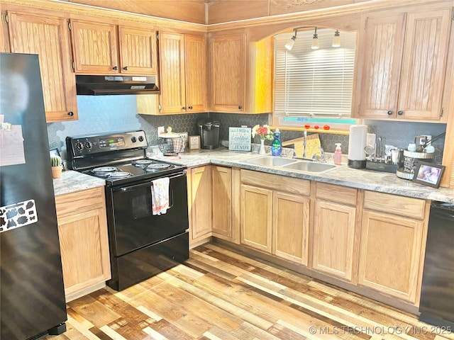 1105 NW 9th St, Stigler, OK 74462 - kitchen with black appliances, under cabinet range hood, light brown cabinets, light countertops, and light wood-type flooring