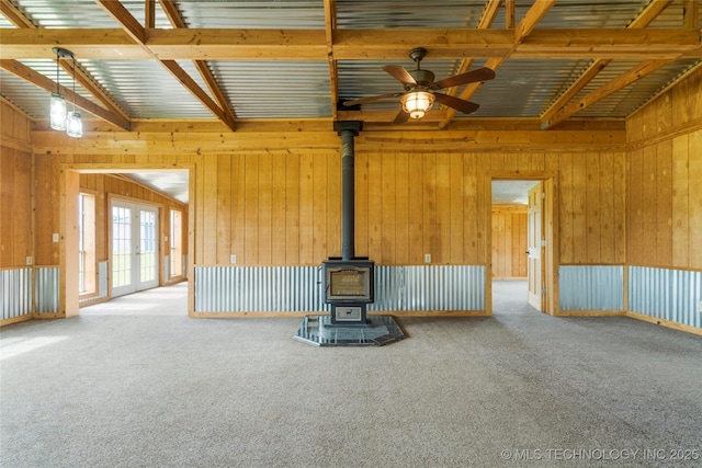 17652 S Hickory St, Sapulpa, OK 74066 - unfurnished living room with carpet flooring, a wood stove, a ceiling fan, wooden walls, and beamed ceiling