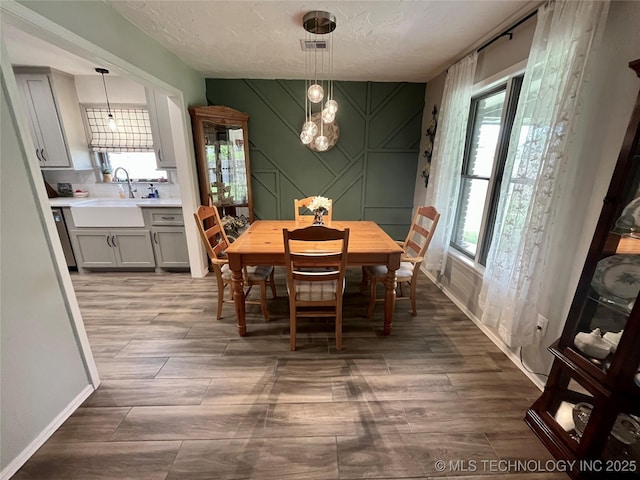 2807 Irving St, Muskogee, OK 74403 - dining space featuring wood finished floors, a textured ceiling, and a chandelier