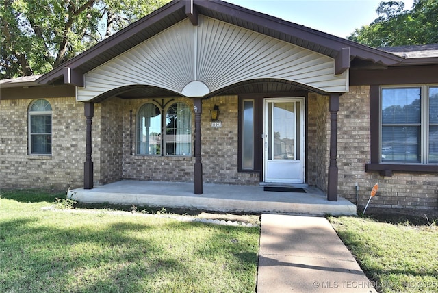 11003 E 27th St, Tulsa, OK 74129 - property entrance with covered porch, brick siding, and a yard