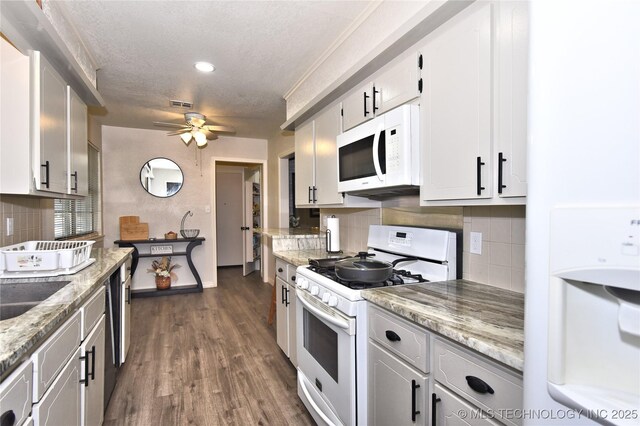 11003 E 27th St, Tulsa, OK 74129 - kitchen with white appliances, decorative backsplash, a ceiling fan, dark wood-style flooring, and light stone counters