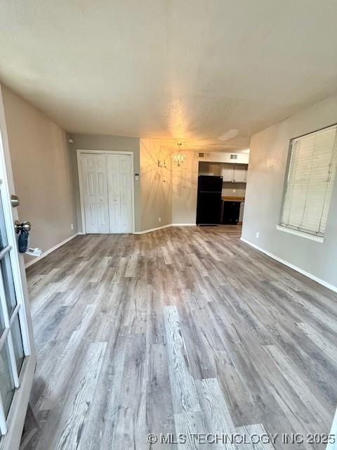 1730 E 67th St Unit K104, Tulsa, OK 74136 - unfurnished living room featuring wood finished floors and a chandelier