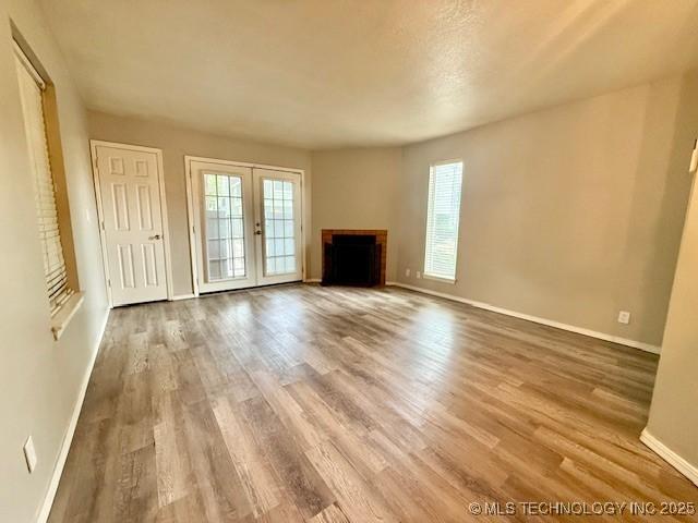 1730 E 67th St Unit K104, Tulsa, OK 74136 - unfurnished living room featuring healthy amount of natural light, wood finished floors, and french doors