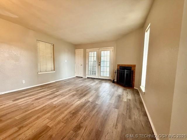 1730 E 67th St Unit K104, Tulsa, OK 74136 - unfurnished living room featuring wood finished floors, french doors, and a fireplace