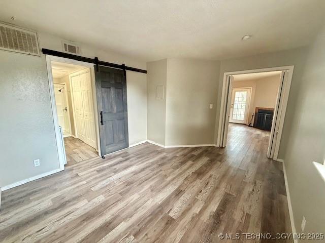 1730 E 67th St Unit K104, Tulsa, OK 74136 - unfurnished room with wood finished floors and a barn door