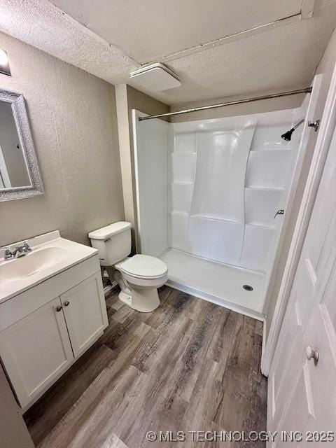 1730 E 67th St Unit K104, Tulsa, OK 74136 - bathroom featuring a textured wall, vanity, wood finished floors, a shower, and a textured ceiling