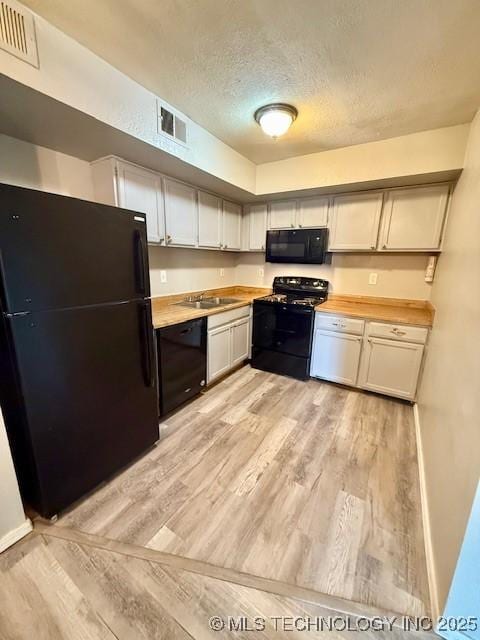 1730 E 67th St Unit K104, Tulsa, OK 74136 - kitchen featuring black appliances, light wood-style flooring, and a textured ceiling