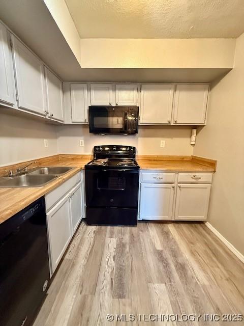 1730 E 67th St Unit K104, Tulsa, OK 74136 - kitchen featuring black appliances, light wood-style floors, white cabinets, and a textured ceiling