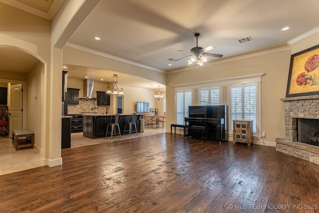 9314 N 96th E Ave, Owasso, OK 74055 - living area with ceiling fan, a chandelier, dark wood-style floors, arched walkways, and a stone fireplace