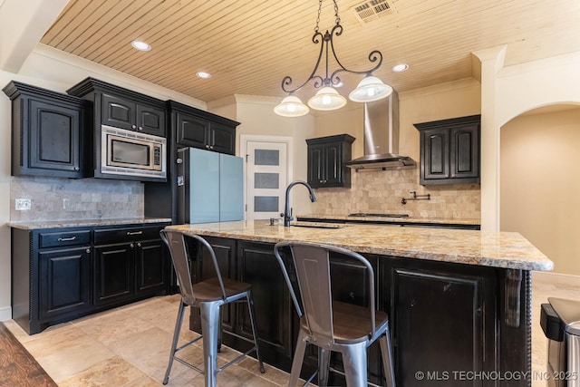 9314 N 96th E Ave, Owasso, OK 74055 - kitchen featuring stainless steel microwave, wall chimney range hood, wooden ceiling, refrigerator, and dark cabinetry