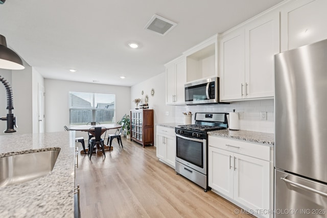 9423 E 132nd Pl S, Bixby, OK 74008 - kitchen featuring stainless steel appliances, white cabinets, decorative backsplash, light wood-type flooring, and recessed lighting