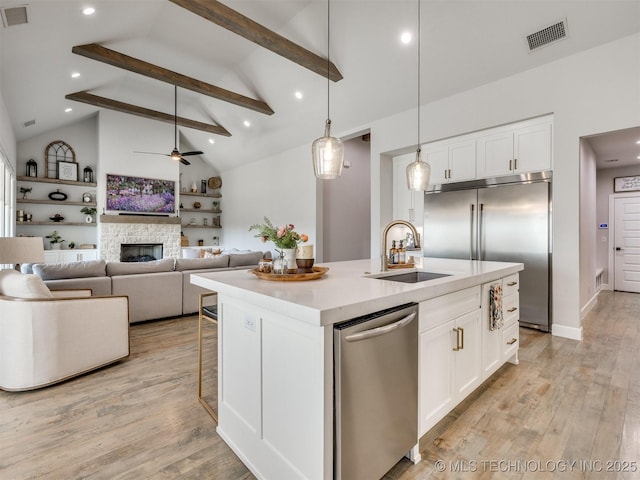 13642 S 21st Pl E, Bixby, OK 74008 - kitchen with appliances with stainless steel finishes, a center island with sink, a ceiling fan, white cabinetry, and beamed ceiling