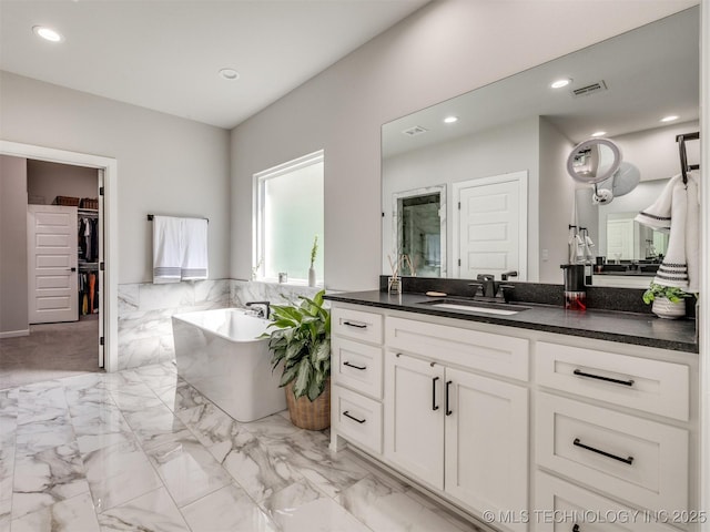 13642 S 21st Pl E, Bixby, OK 74008 - bathroom with vanity, a freestanding bath, a walk in closet, recessed lighting, and marble look tile flooring