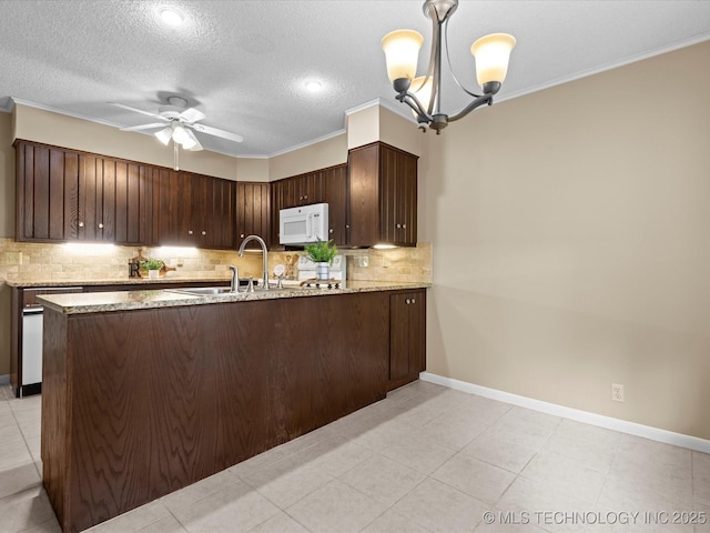 1525 Pecan Pl, Bartlesville, OK 74003 - kitchen with white microwave, dark brown cabinetry, backsplash, a chandelier, and light stone counters
