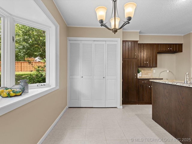 1525 Pecan Pl, Bartlesville, OK 74003 - kitchen featuring dark brown cabinets, backsplash, a chandelier, crown molding, and hanging light fixtures