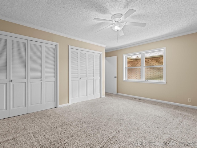 1525 Pecan Pl, Bartlesville, OK 74003 - unfurnished bedroom with ornamental molding, a textured ceiling, two closets, carpet, and ceiling fan