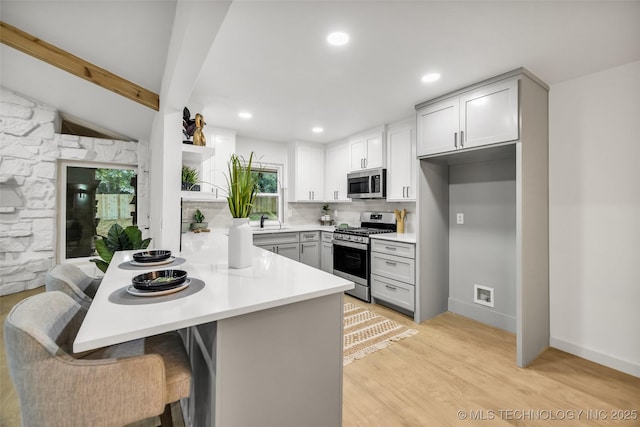 4235 E 104th St, Tulsa, OK 74137 - kitchen featuring stainless steel appliances, open shelves, a peninsula, light countertops, and light wood finished floors