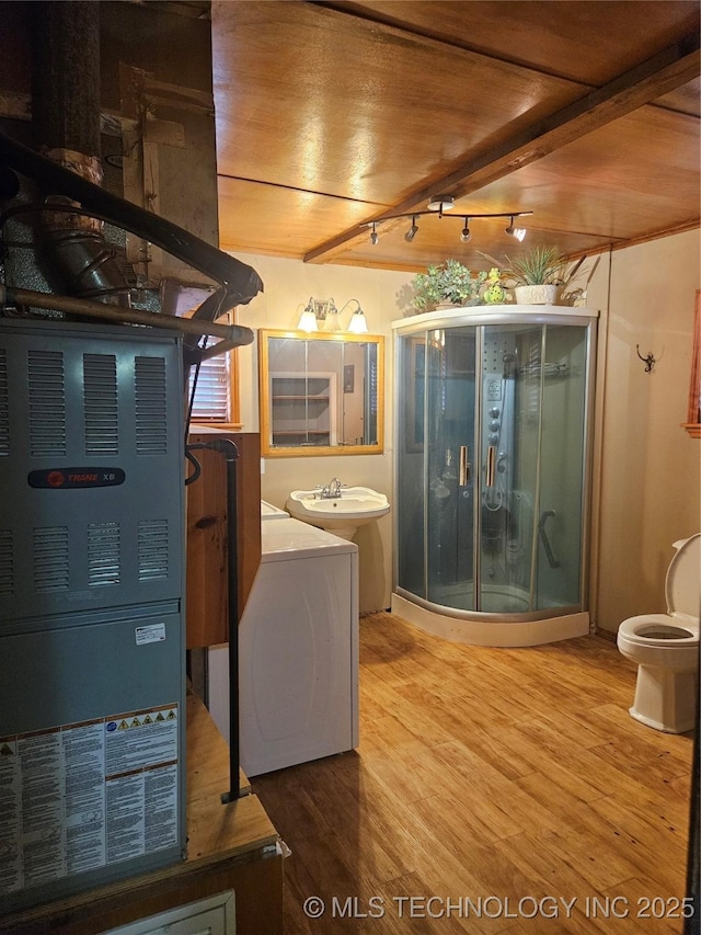 307 N Hartman Ave, Cushing, OK 74023 - bathroom featuring rail lighting, a shower stall, wood finished floors, vanity, and independent washer and dryer