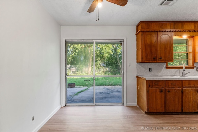 3344 S 120th E Ave, Tulsa, OK 74146 - kitchen with light countertops, brown cabinets, healthy amount of natural light, light wood-type flooring, and a textured ceiling