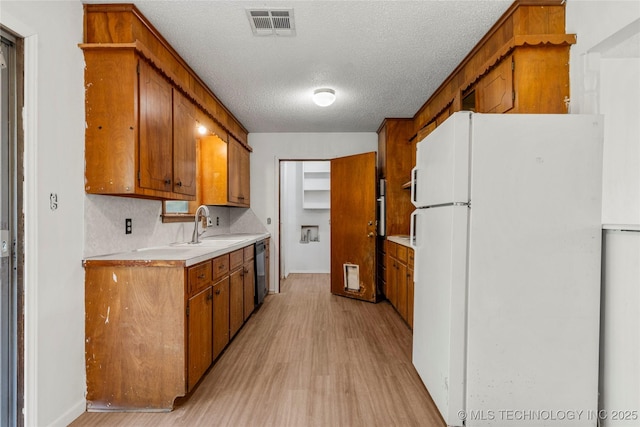 3344 S 120th E Ave, Tulsa, OK 74146 - kitchen with freestanding refrigerator, light wood finished floors, brown cabinetry, and a textured ceiling