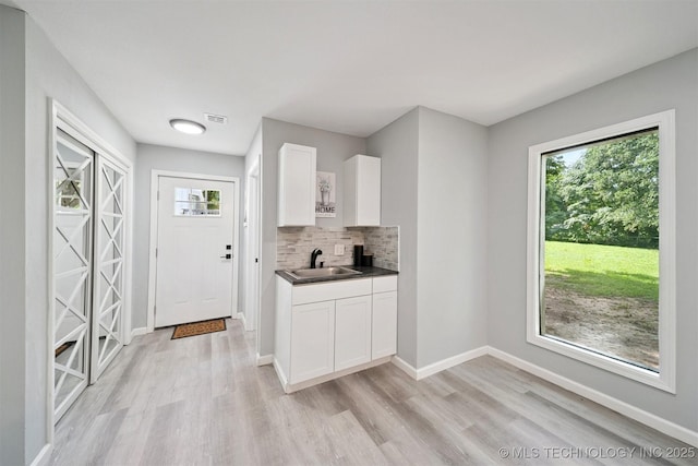 412 W Roger St, Oilton, OK 74052 - kitchen featuring light wood-style floors, white cabinetry, tasteful backsplash, and dark countertops