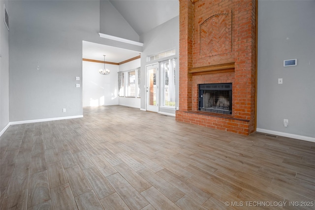 16304 Bandera, Oklahoma City, OK 73013 - unfurnished living room featuring a chandelier, a brick fireplace, wood finished floors, and high vaulted ceiling