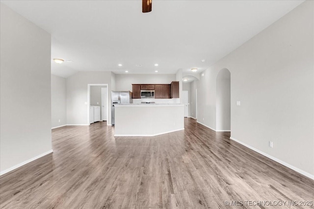 3729 S 150th E Ave, Tulsa, OK 74134 - unfurnished living room with arched walkways, light wood-style flooring, recessed lighting, and washer / clothes dryer