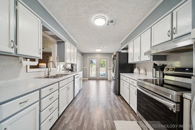 208 N Davis Ave W, Claremore, OK 74017 - kitchen with appliances with stainless steel finishes, under cabinet range hood, a textured ceiling, light countertops, and white cabinetry