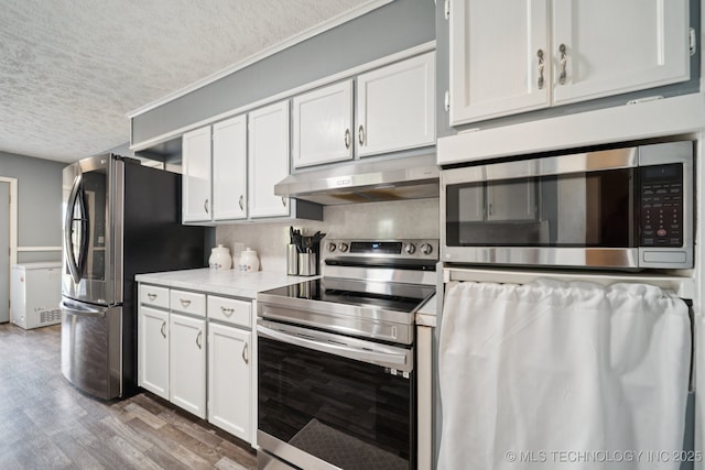 208 N Davis Ave W, Claremore, OK 74017 - kitchen featuring appliances with stainless steel finishes, under cabinet range hood, a textured ceiling, light countertops, and wood finished floors