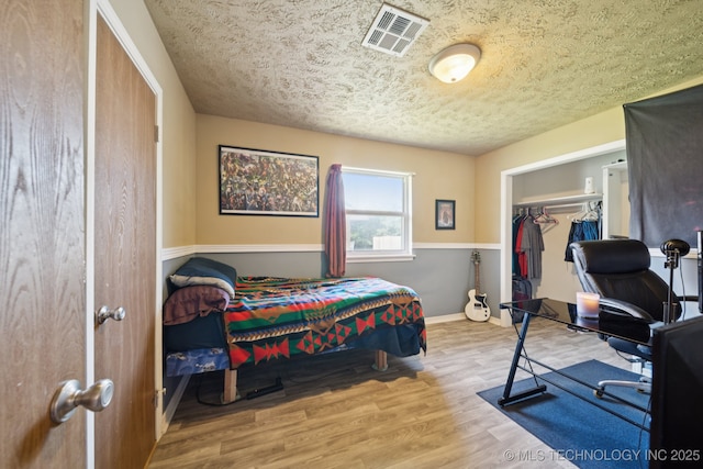 208 N Davis Ave W, Claremore, OK 74017 - bedroom with wood finished floors, a textured ceiling, a closet, and an office area