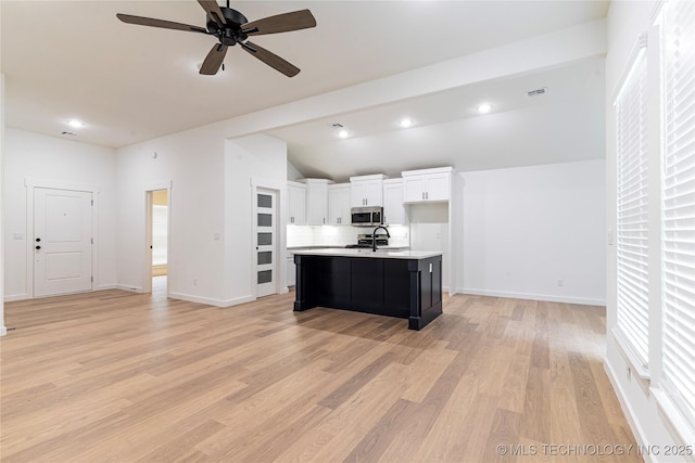 214 S 26th St, Collinsville, OK 74021 - kitchen featuring stainless steel microwave, light countertops, ceiling fan, open floor plan, and light wood-style floors