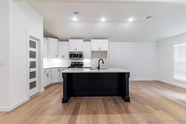 214 S 26th St, Collinsville, OK 74021 - kitchen featuring stainless steel microwave, stove, vaulted ceiling, backsplash, and light wood-style floors