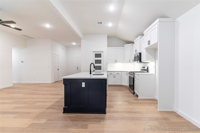 214 S 26th St, Collinsville, OK 74021 - kitchen featuring stainless steel appliances, a ceiling fan, light wood finished floors, tasteful backsplash, and an island with sink