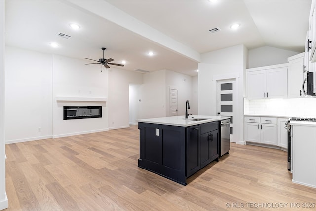 214 S 26th St, Collinsville, OK 74021 - kitchen featuring a ceiling fan, a center island with sink, light wood-style flooring, dark cabinets, and vaulted ceiling