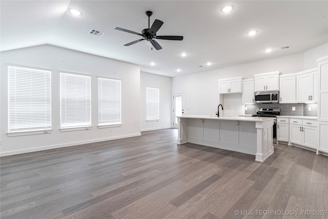 302 S 26th St, Collinsville, OK 74021 - kitchen with stainless steel appliances, a ceiling fan, decorative backsplash, wood finished floors, and white cabinetry