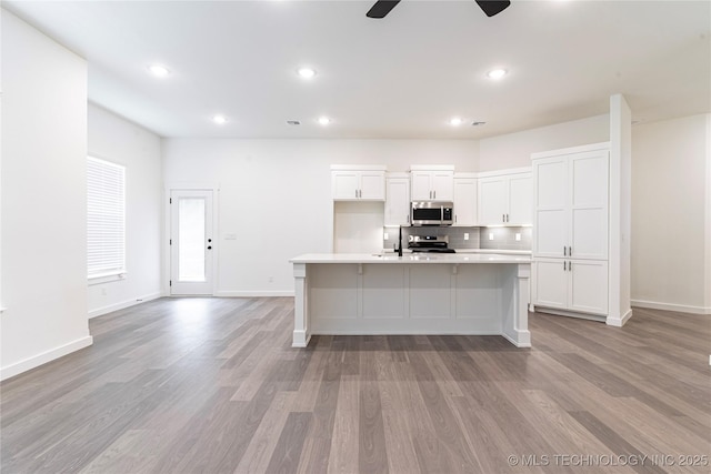 302 S 26th St, Collinsville, OK 74021 - kitchen with appliances with stainless steel finishes, white cabinetry, light wood-style flooring, decorative backsplash, and recessed lighting