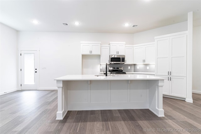 302 S 26th St, Collinsville, OK 74021 - kitchen featuring stainless steel microwave, light wood-type flooring, light countertops, white cabinetry, and recessed lighting