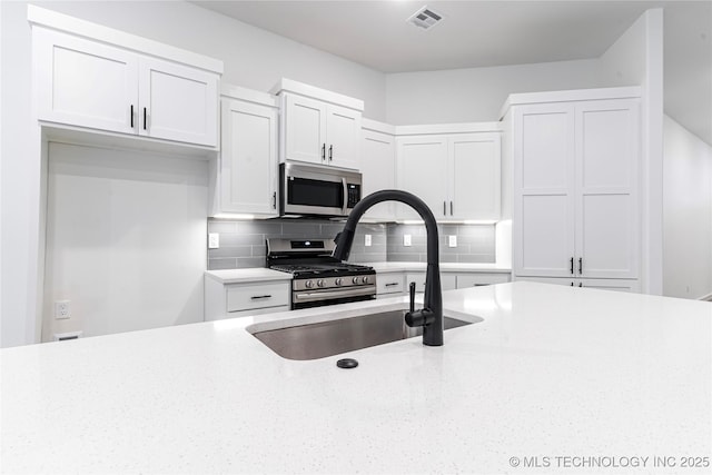 302 S 26th St, Collinsville, OK 74021 - kitchen with stainless steel appliances, decorative backsplash, white cabinets, and light stone countertops