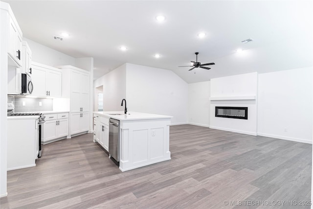 302 S 26th St, Collinsville, OK 74021 - kitchen featuring stainless steel appliances, a ceiling fan, light wood-style flooring, an island with sink, and vaulted ceiling