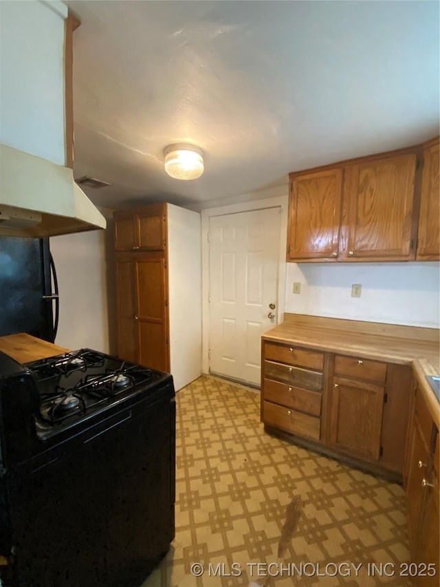 41 G SE, Ardmore, OK 73401 - kitchen featuring black gas range oven, brown cabinets, and light flooring