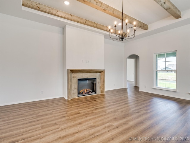 7202 E 132nd St S, Bixby, OK 74008 - unfurnished living room featuring arched walkways, beamed ceiling, wood finished floors, a chandelier, and a premium fireplace