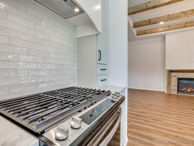 7202 E 132nd St S, Bixby, OK 74008 - kitchen featuring stainless steel gas range, wood finished floors, decorative backsplash, light stone countertops, and a fireplace