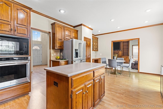 9810 E 96th Pl, Tulsa, OK 74133 - kitchen with stainless steel appliances, ornamental molding, a kitchen island, brown cabinetry, and recessed lighting