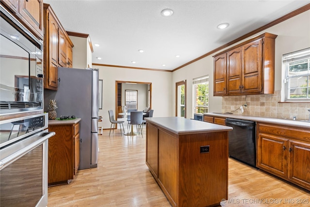 9810 E 96th Pl, Tulsa, OK 74133 - kitchen featuring stainless steel appliances, a kitchen island, crown molding, light wood-style flooring, and decorative backsplash