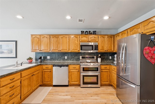 1600 S Ironwood Ave, Broken Arrow, OK 74012 - kitchen featuring appliances with stainless steel finishes, light wood-style floors, dark countertops, brown cabinets, and recessed lighting