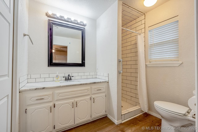 2520 Arlington Blvd, Ada, OK 74820 - bathroom featuring vanity, wood finished floors, a stall shower, and decorative backsplash