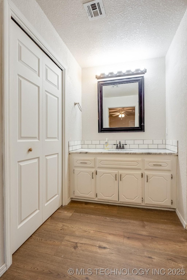 2520 Arlington Blvd, Ada, OK 74820 - bathroom with vanity, wood finished floors, a textured ceiling, and a textured wall