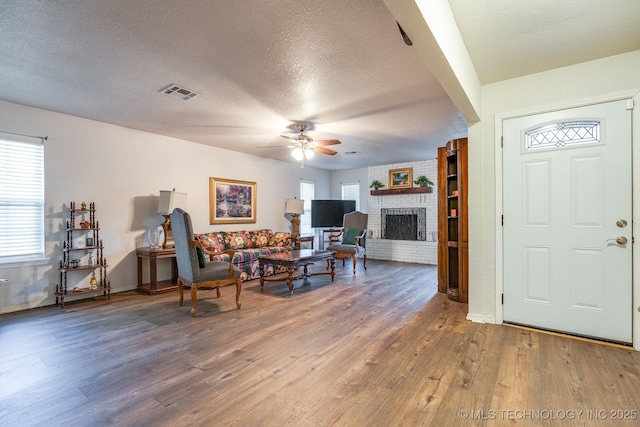 2520 Arlington Blvd, Ada, OK 74820 - living area featuring a ceiling fan, a textured ceiling, wood finished floors, and a brick fireplace